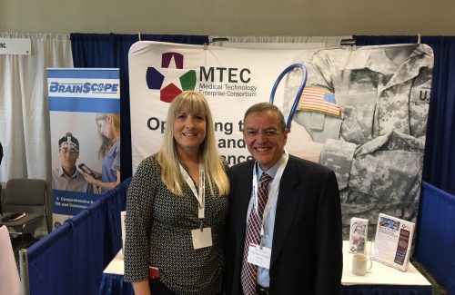 image of Stacey Lindbergh and President Dr. Lester Martinez Lopez in front of MTEC booth at members meeting